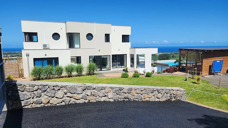La villa au-dessus de son mur de pierre, l'océan au loin