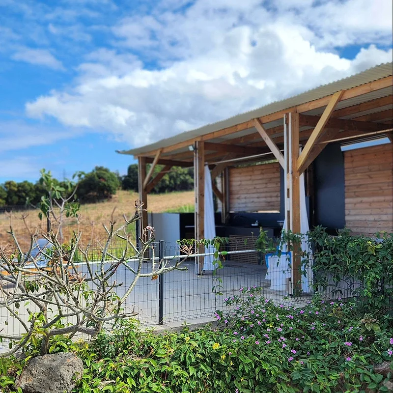 La cuisine extérieure sous sa charpente en bois, au milieu du jardin