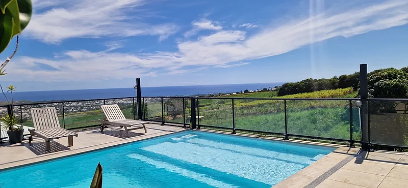 La piscine à débordement, ses transats et la côte du sud de l'île jusqu'à l'océan