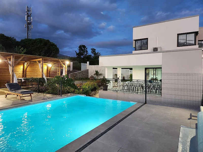 La piscine à la tombée du jour, la cuisine extérieure éclairée