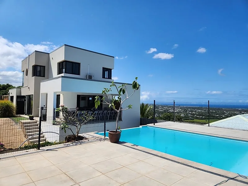 La terrasse dallée au bord de la piscine, la mer au loin